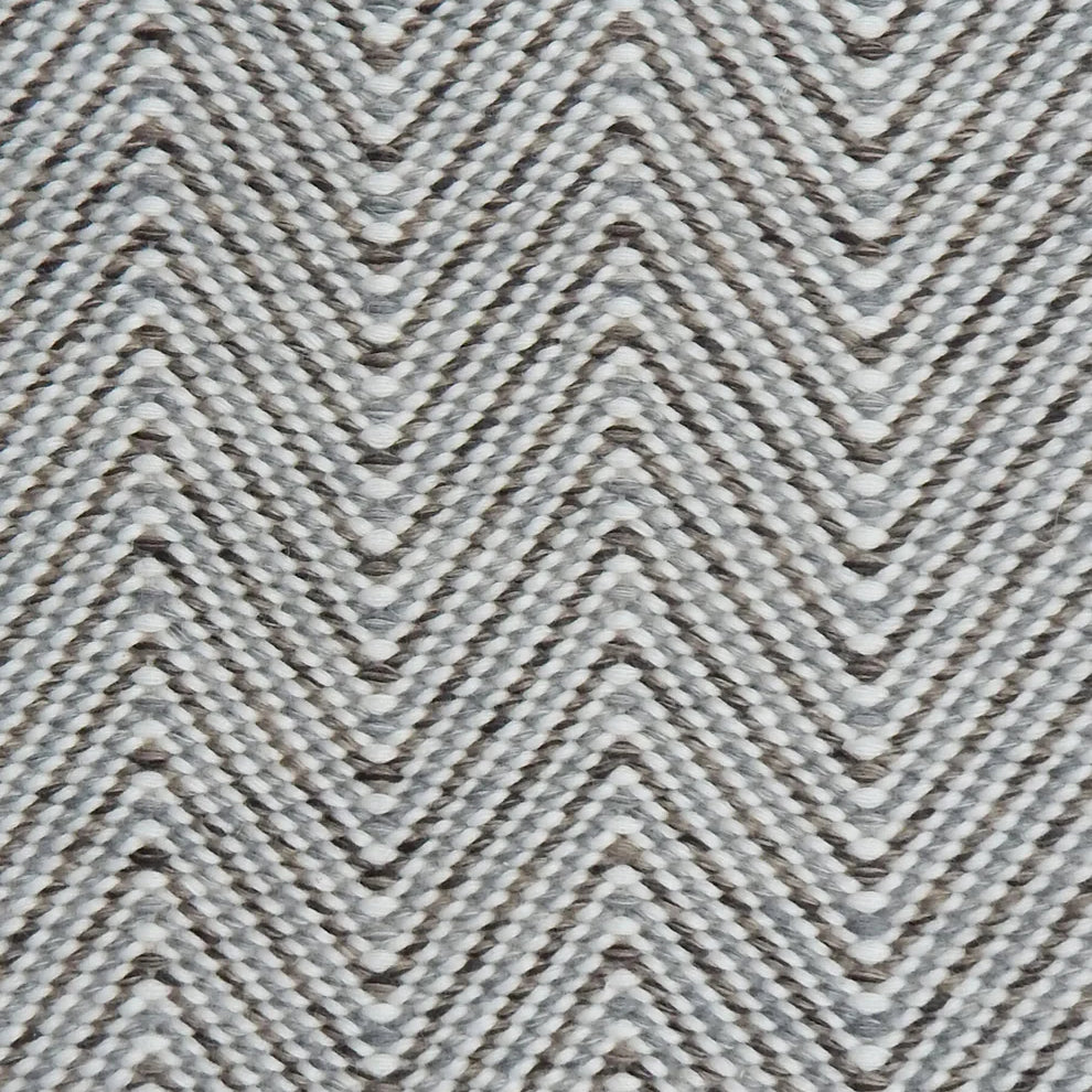 Handwoven rug in a herringbone pattern in shades of grey and white. 