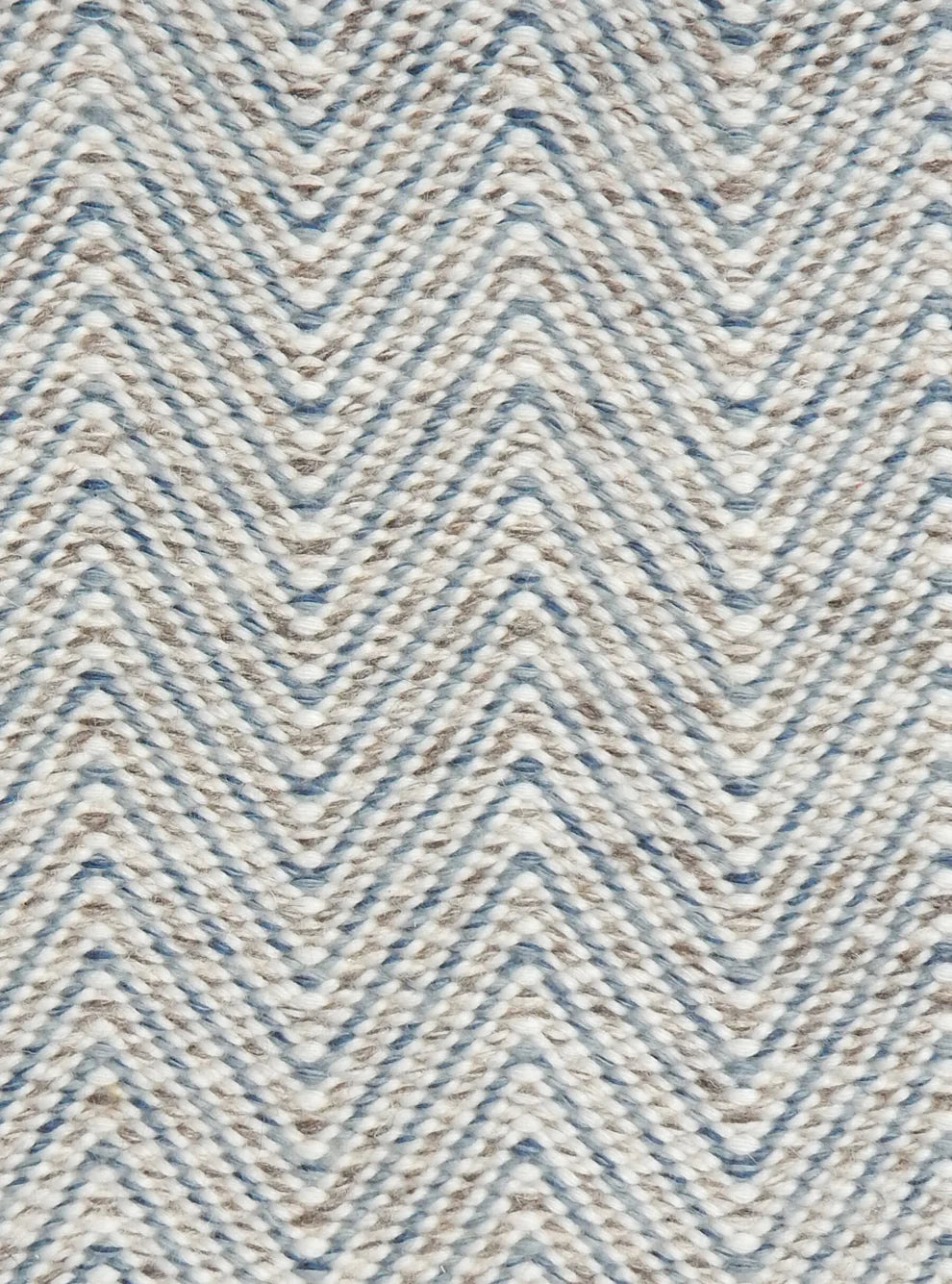 Handwoven rug in a herringbone pattern in blue, grey and white. 