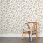 Wooden chair against a floral wallpapered wall