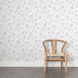 Wooden chair against a blue and white floral wallpapered wall