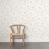 Wooden chair against a tan and white floral wallpapered wall