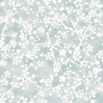 Detail of wallpaper in a painterly branch print in white on a light blue watercolor field.