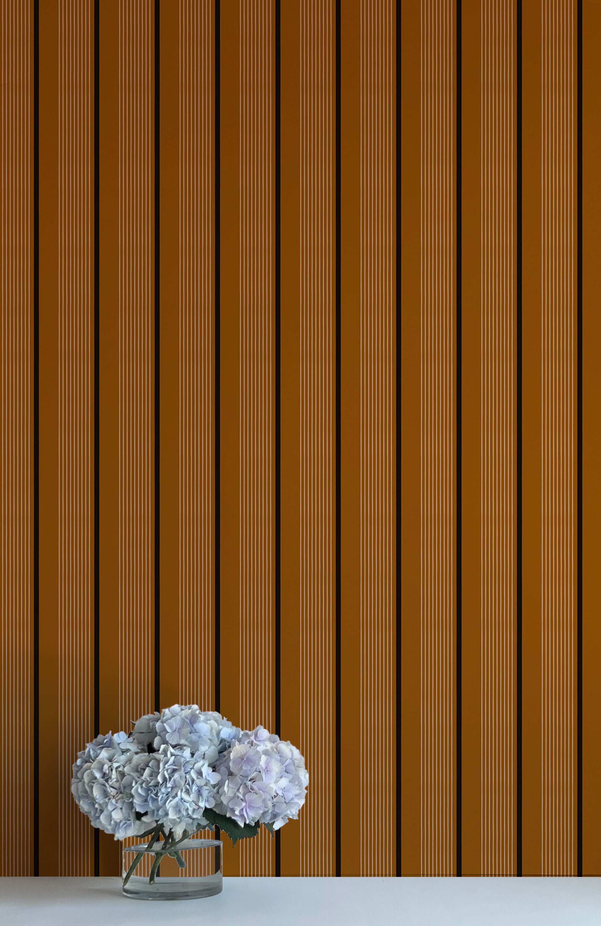 Striped brown wall with a vase of white flowers on a white surface