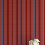 Striped red and blue wallpaper with a vase of flowers on a matching surface.