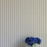 Striped wallpaper with a vase of blue flowers in the foreground