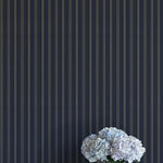 Vase of white flowers against a dark blue striped wall