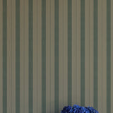 Striped wallpaper with a vase of blue flowers in the foreground