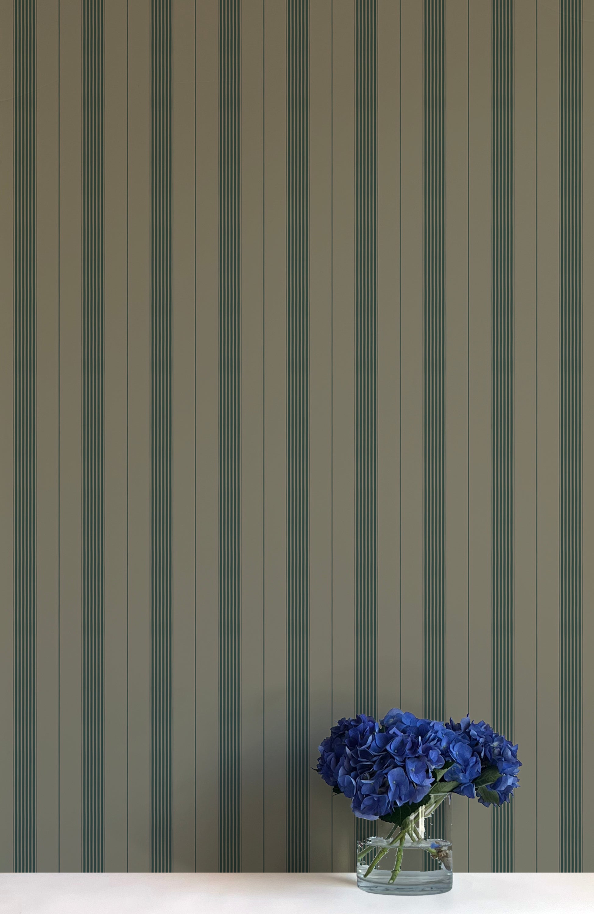 Striped wallpaper with a vase of blue flowers in the foreground
