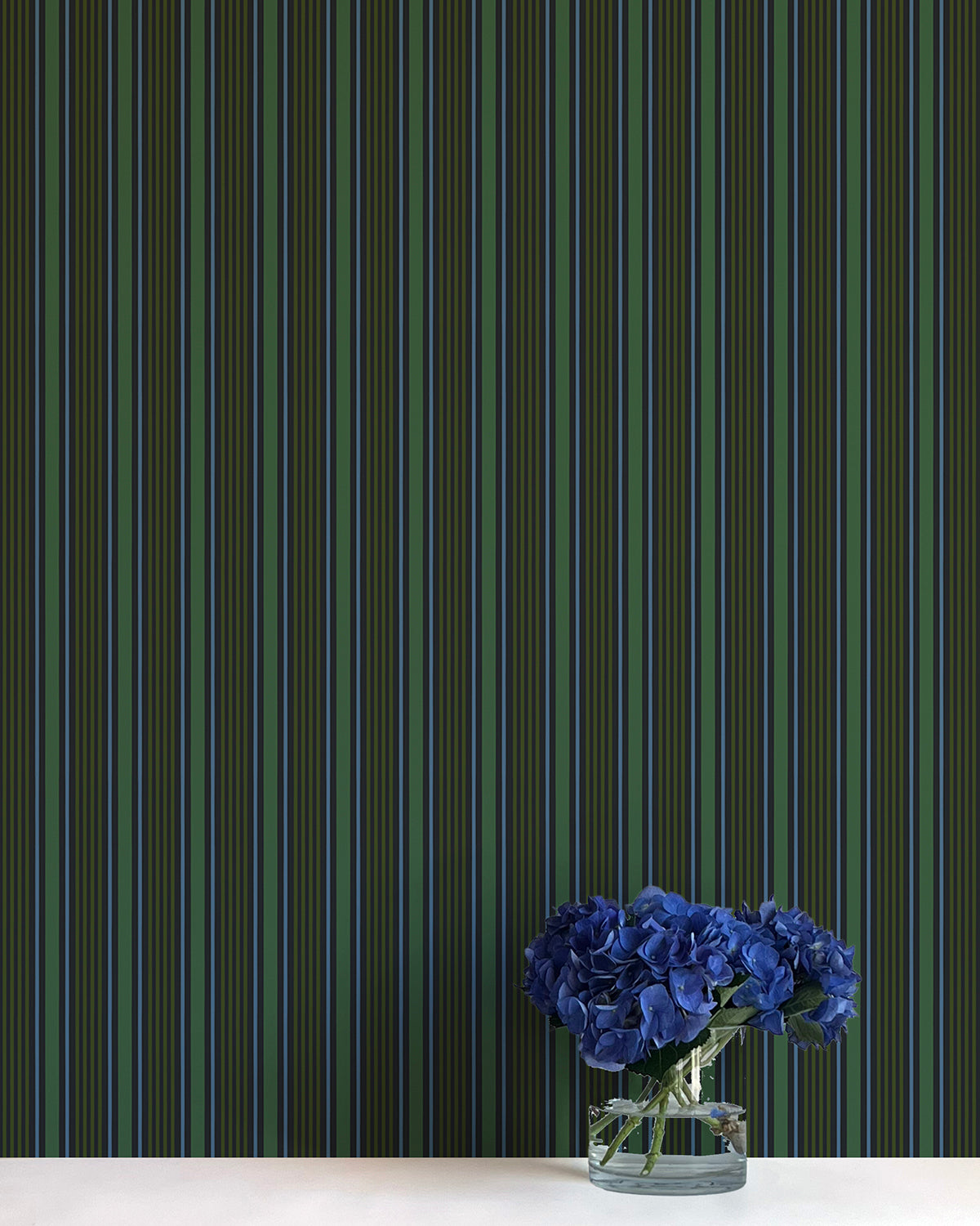 Striped wallpaper with a vase of blue flowers on a white surface