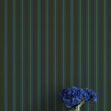 Striped wallpaper with a vase of blue flowers on a white surface