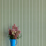 Blue pitcher with flowers against a green striped wallpaper background