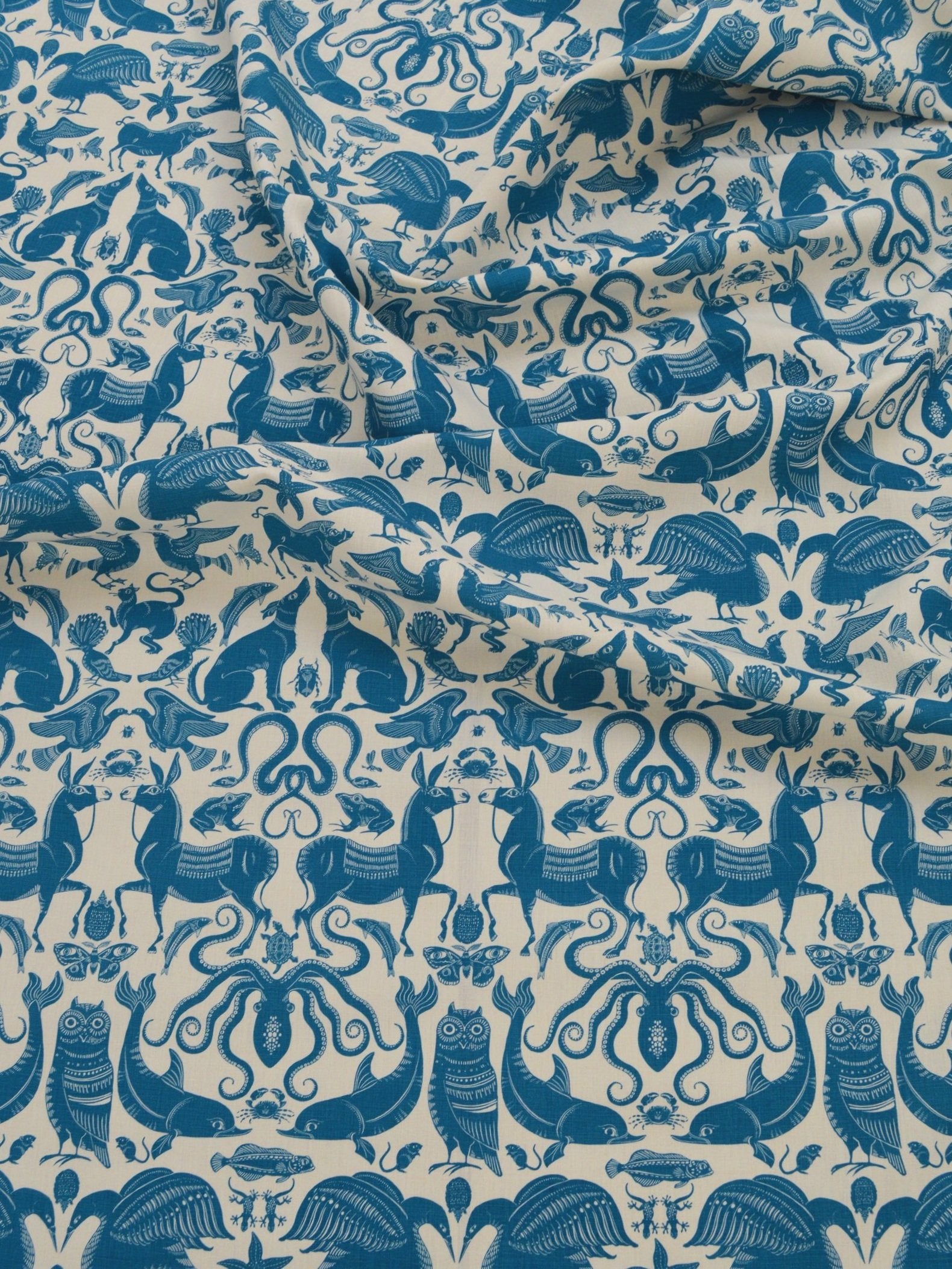Draped patterned fabric with animals and sea creatures in blue on a white background