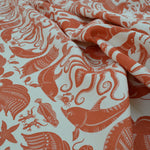 Draped patterned fabric with animals and sea creatures in orange on a white background