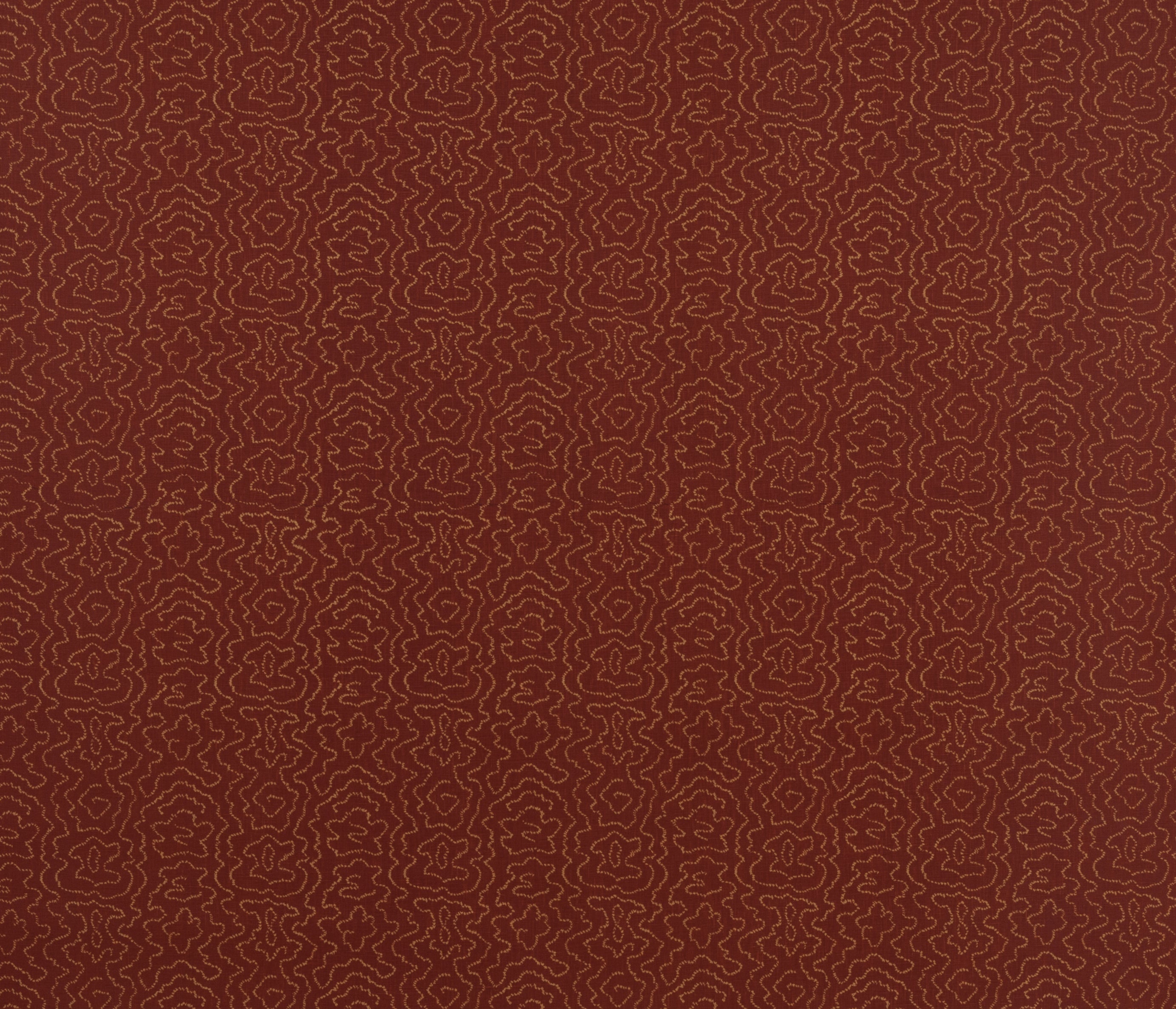 Detail of fabric in a minimalist wood grain print in tan on a rust field.