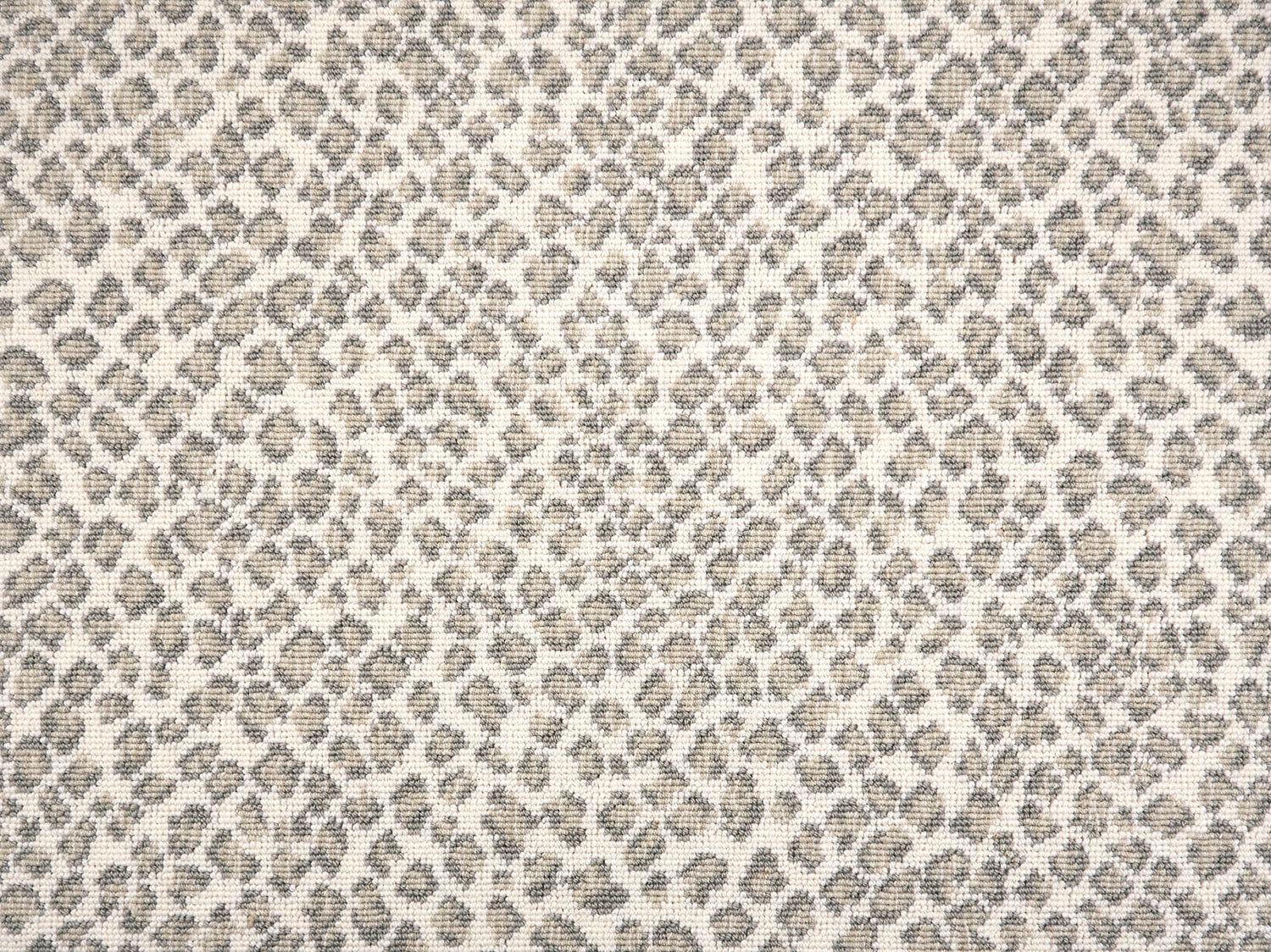 A close-up of a leopard print broadloom in grey and beige spots on a cream background.