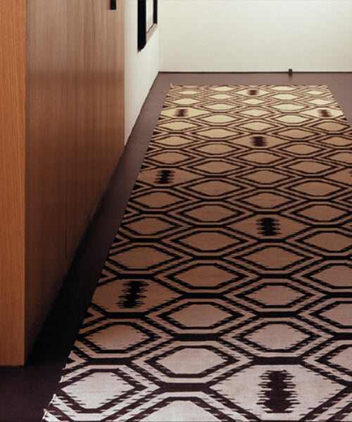 Patterned rug on a wooden floor next to a wall.