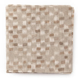 A stack of fabric swatches in a painterly checked pattern in shades of tan and brown.