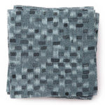 A stack of fabric swatches in a painterly checked pattern in shades of blue and navy.