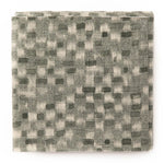 A stack of fabric swatches in a painterly checked pattern in shades of olive.