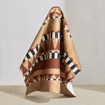 Draped swatch of bold geometric printed fabric in brown and tan with black and white accents.