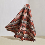 Hanging fabric in a complex stripe with geometric shapes and chevrons in clay, lilac, brown and cream.