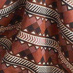 Fabric in a complex stripe with geometric shapes and chevrons in clay, lilac, brown and cream.