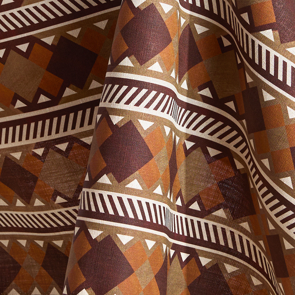 Fabric in a complex stripe with geometric shapes and chevrons in taupe, orange, oxblood and cream.