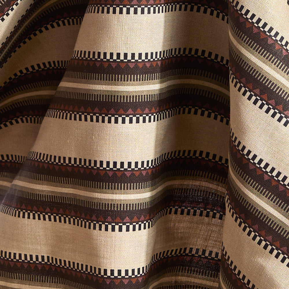 Fabric in complex geometric stripe in brown, tan, orange, light purple and black on a cream field.
