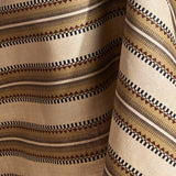 Fabric in a complex geometric stripe in brown, tan, orange, light purple and black on a cream field.
