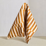 Draped fabric in a trompe l'oeil stripe pattern with geometric shapes in cream and ochre.