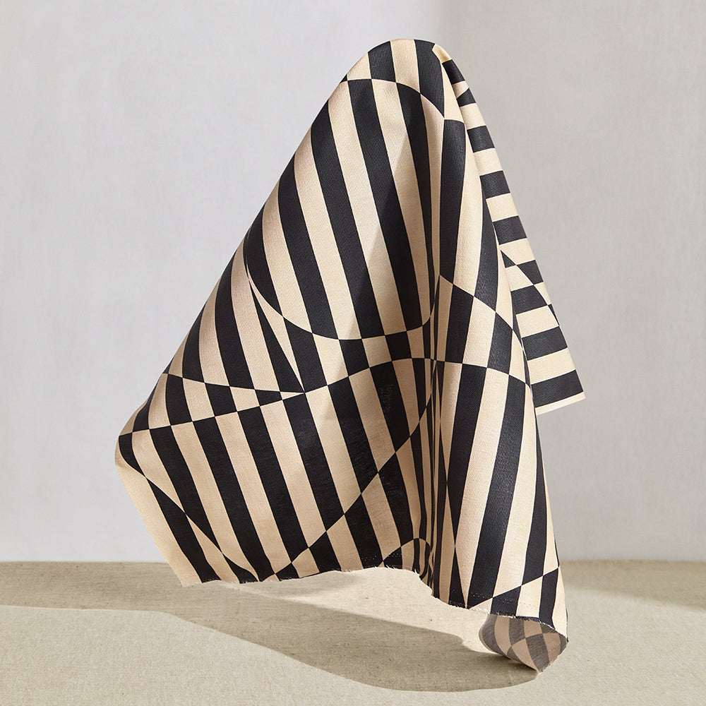 Draped fabric in a trompe l'oeil stripe pattern with geometric shapes in cream and black.