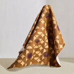 Hanging fabric in a curvilinear art deco inspired pattern in ochre, beige and purple.