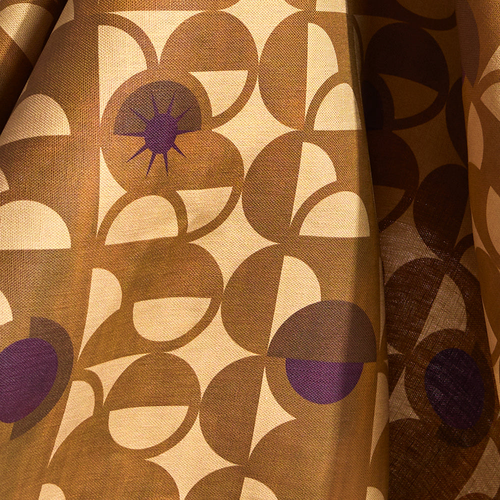 Fabric in a curvilinear art deco inspired pattern in ochre, beige and purple.