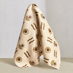 Hanging fabric in a graphic geometric pattern of circles, stars and stripes in taupe and brown on a cream field.