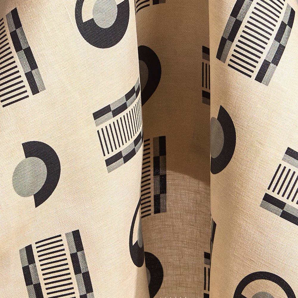 Fabric in a graphic geometric pattern of circles, and stripes in black and grey on a cream field.
