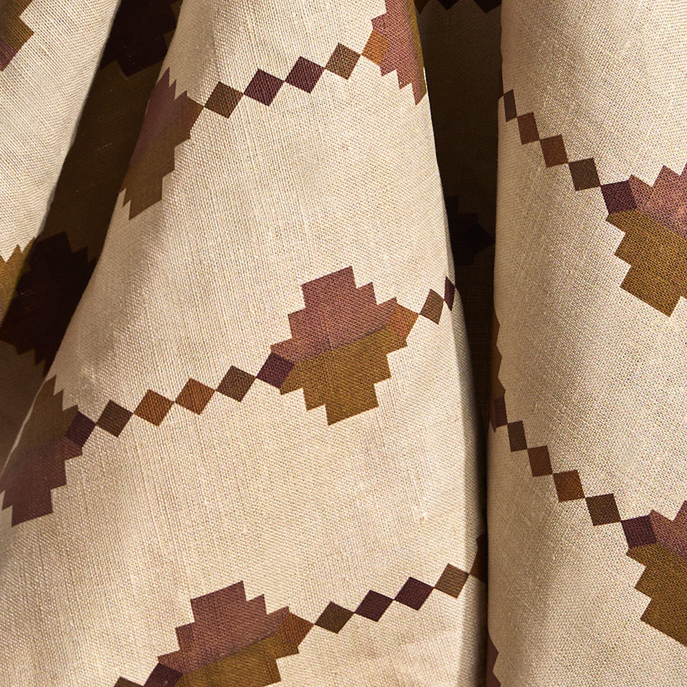 Fabric in a stacked diamond stripe design in pink and ochre with purple accents.