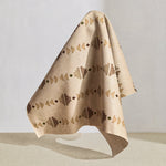 Hanging fabric in a geometric stair step pattern in blush, taupe, grey, olive and brown on a cream field.