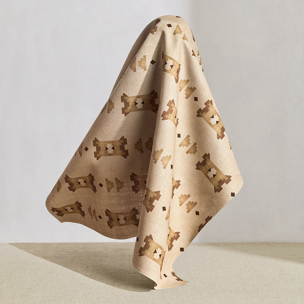 Hanging fabric in a geometric stair step pattern in brown and tan on a cream field.