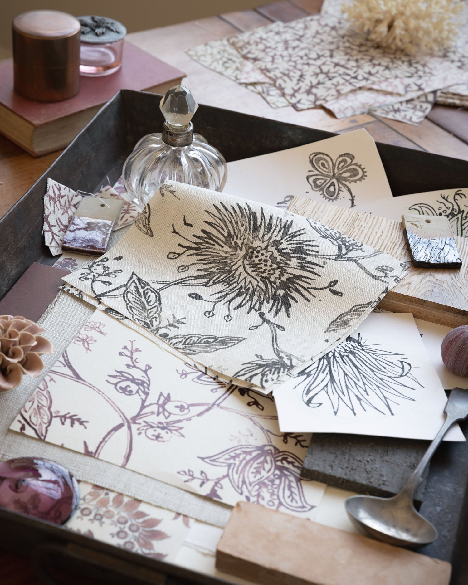 Desk scene with layers of watercolor floral swatches in various colors with natural specimens and vintage props. 
