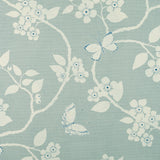 Detail of fabric in a flower and butterfly print in cream and blue on a turquoise field.