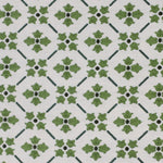 Detail of fabric in a repeating floral lattice print in shades of green on a white field.