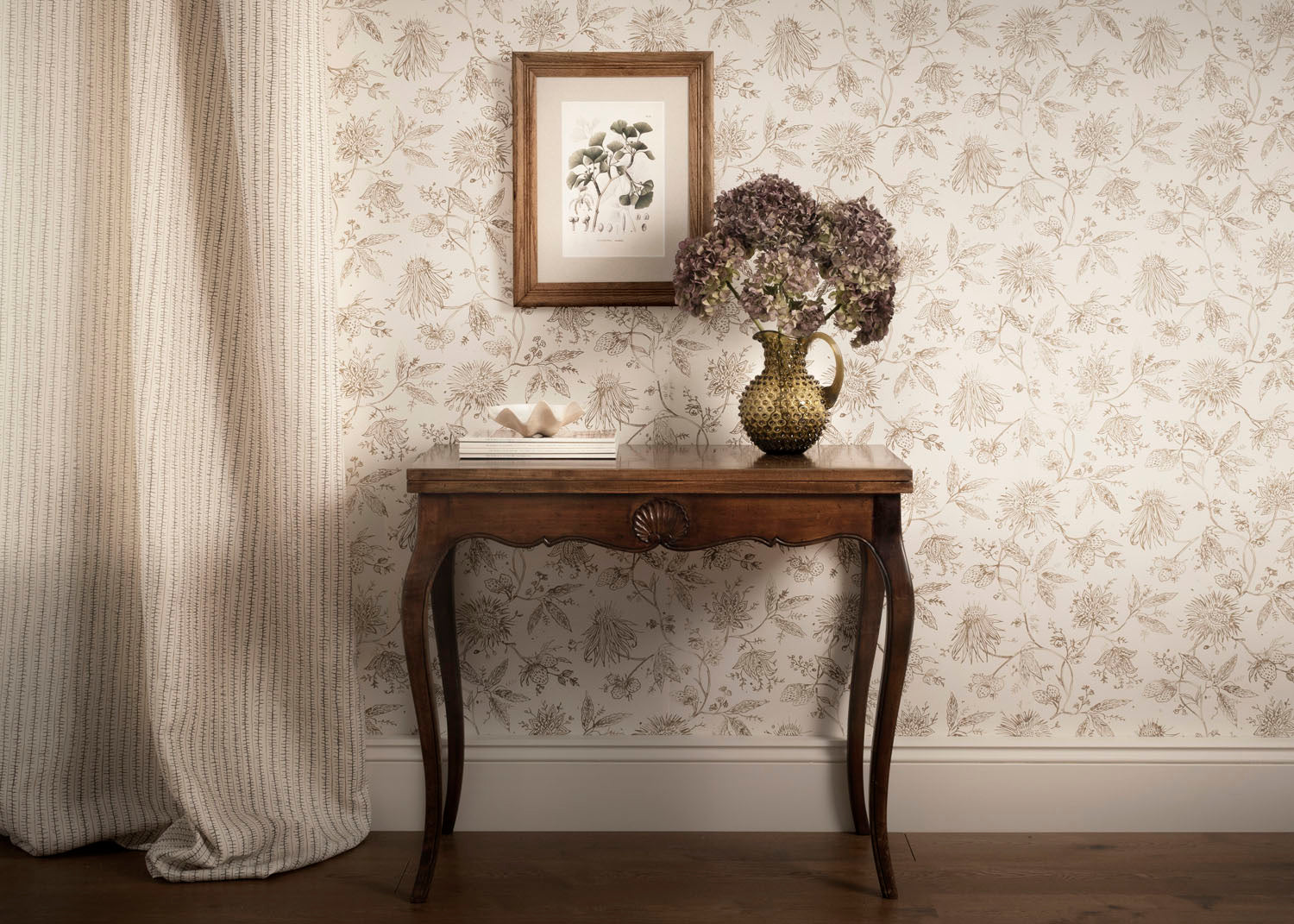 Wooden side table with decorative items against a floral wallpapered wall.