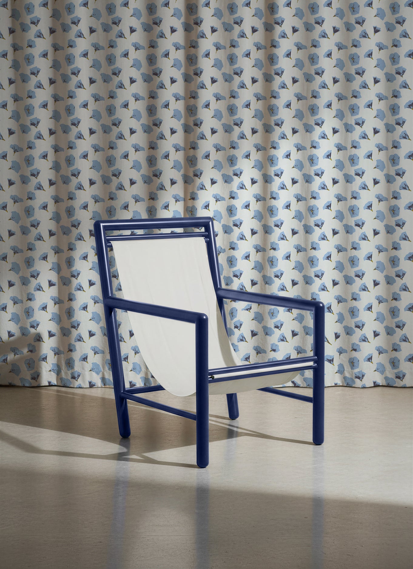 Blue chair in front of a blue floral patterned curtain