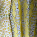 Draped fabric in yellow butterfly stripe against yellow floral wallpaper. 