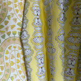 Draped fabric in yellow butterfly stripe against yellow floral wallpaper. 