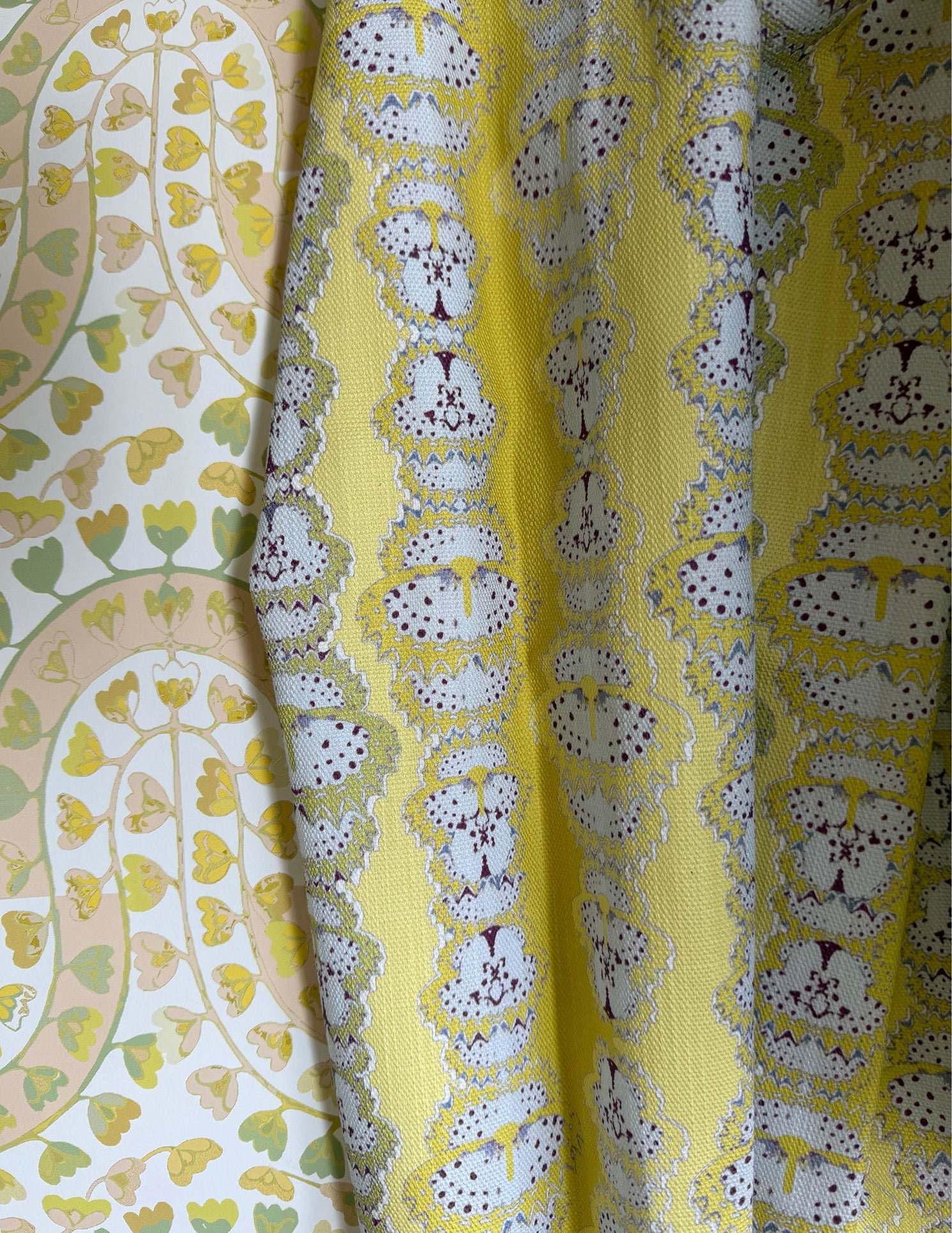 Draped fabric in yellow butterfly stripe against yellow floral wallpaper. 