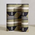 Wallpaper roll in a graphic geometric design in sage green, taupe, white and black.