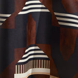 Wallpaper in a graphic geometric design in burn siena, black, taupe and cream.