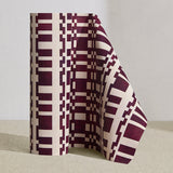 Wallpaper roll in a modernist checkerboard pattern in maroon and cream.