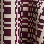 Printed wallpaper in a modernist checkerboard pattern in maroon and cream.
